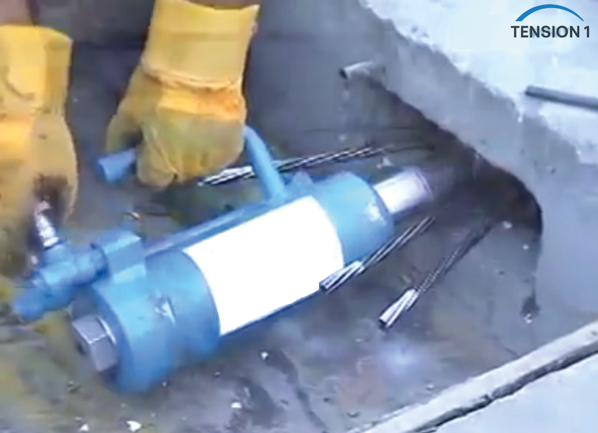 Hydraulic jack stressing a monostrand tendon at the slab edge, a key step in the post tension slab stressing checklist