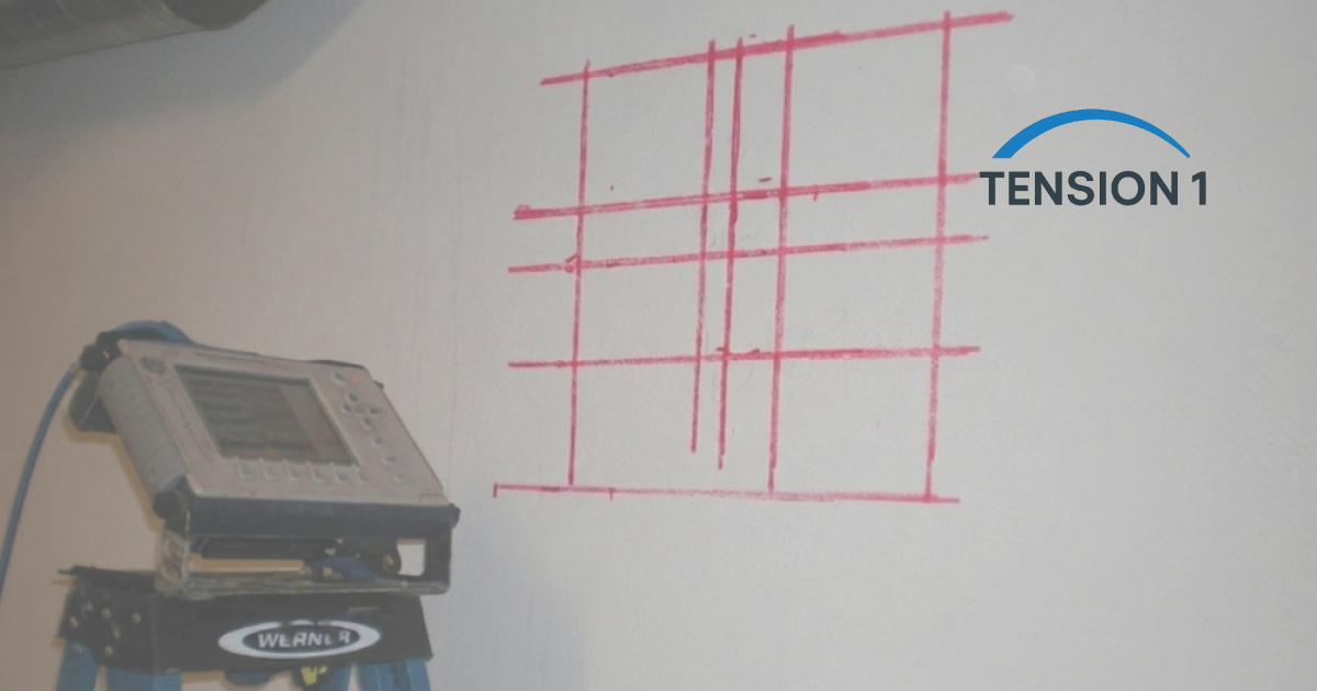 GPR scanner beside a concrete surface marked in red with located tendon and rebar lines before drilling a post tension slab