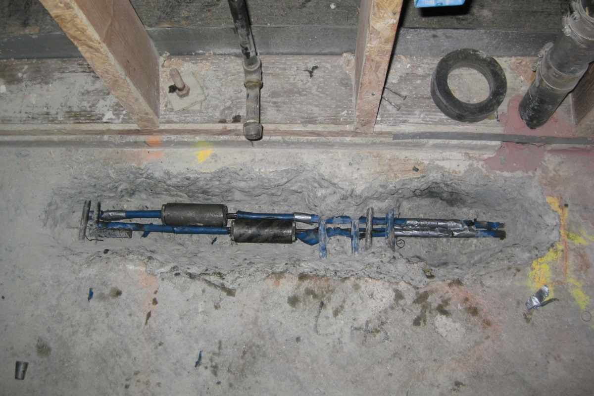 Mechanical couplers joining severed strands inside a chase cut into a post tension slab