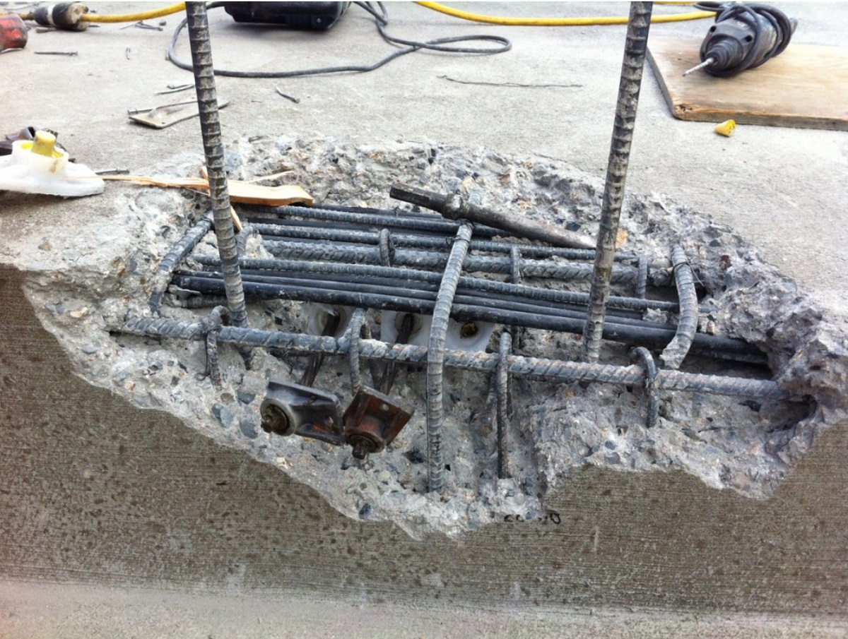 Concrete blowout exposing reinforcement in the anchorage zone of a post tension slab