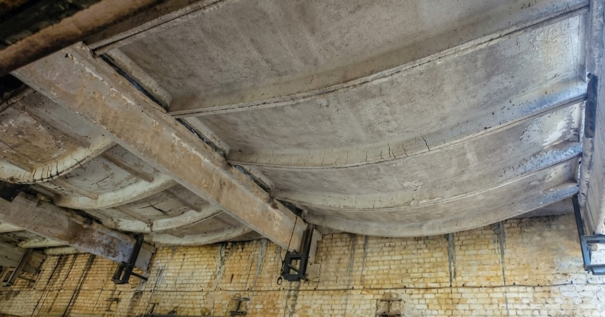 Underside of a reinforced concrete slab on beams showing visible sag, the long-term deflection a post tension slab is designed to limit
